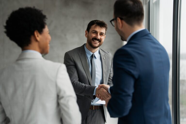 Interviewee shaking hands with interviewer for job interview, smilling