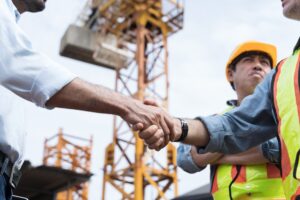 Team of male engineers in safety vests shake hands