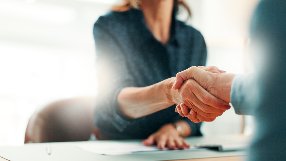 Handshake, deal and business people in office with partnership, contract or finance agreement. Meeting, welcome and financial advisor shaking hands with investor for investment negotiation at agency.