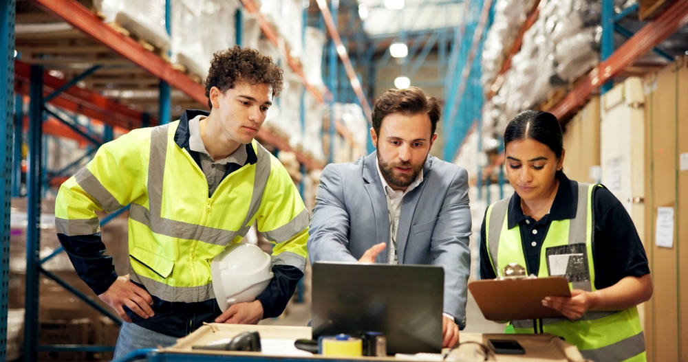 Executive team member works with engineers in warehouse