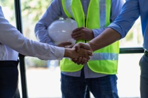 Employees in safety vests shaking hands, new hires