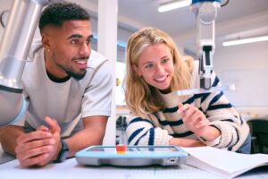 A Male and female engineering student working together with mechanical equipment.
