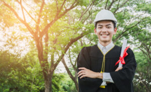 Engineering graduate holding diploma and wearing a hard hat.